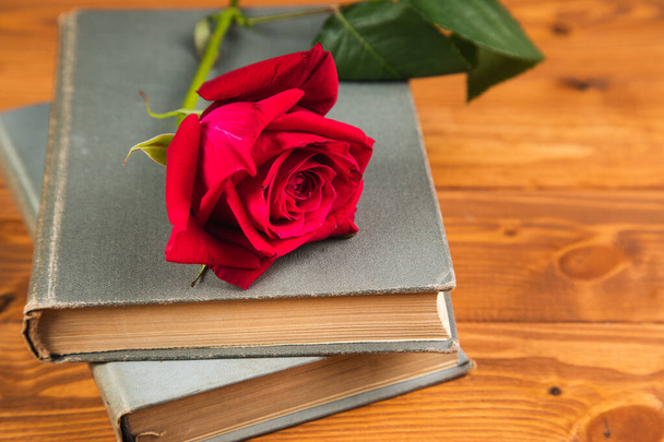 rode roos op een boek op een houten achtergrond - Foto, afbeelding