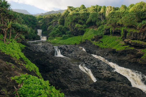 Dramatyczna seria wodospadów Ohe 'o Gulch spływających po skale pod mostem, w Parku Narodowym Haleakala, Kipahula, Maui, Hawaje, USA. Wysokiej jakości zdjęcie - Zdjęcie, obraz