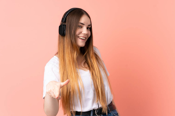 Nuori valkoihoinen nainen eristetty vaaleanpunainen tausta kuuntelee musiikkia - Valokuva, kuva