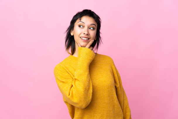 Young Uruguayan woman over isolated pink background looking up while smiling - Fotografie, Obrázek