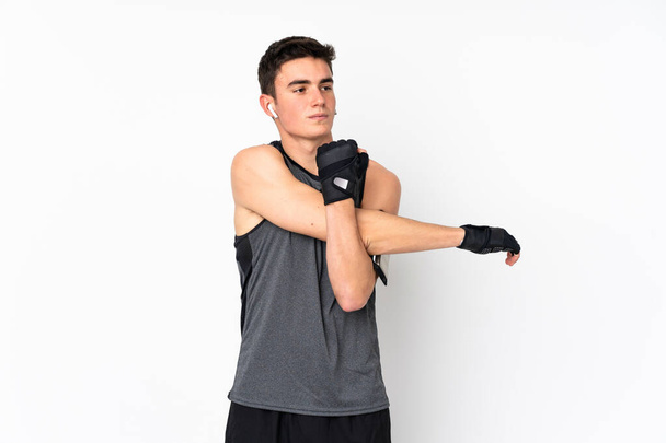 Teenager sport man over isolated white wall stretching arm - Foto, afbeelding