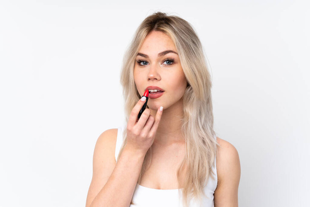 Adolescente blonde fille sur fond blanc isolé tenant rouge à lèvres - Photo, image