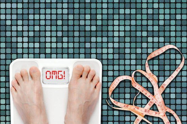 Femme sur la balance de salle de bain affichant le message OMG. Concept d'embonpoint, d'obésité ou de mode de vie malsain avec ruban à mesurer sur le sol de la salle de bain. - Photo, image