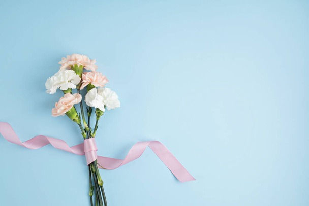 Bouquet of pink carnation flowers over blue background. Saint valentine, mothers day idea - Photo, Image