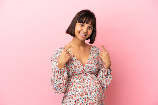 Giovane donna incinta su isolato sfondo rosa dando un pollice in su gesto - Foto, immagini