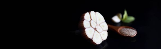 Frische Knoblauchzehe auf schwarzem Hintergrund. Knoblauch ist reich an Vitaminen, nützlichem Frühling, guten Gewürzen. Knoblauch in Scheiben geschnitten auf dunklem Hintergrund. Roh geschnittener Knoblauch. - Foto, Bild