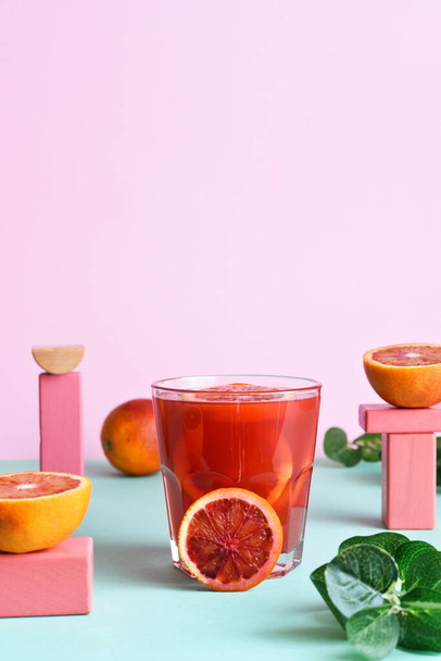 Red orange juice in a glass with geometric shapes. Pop trend 2021. The concept of beautiful food. - Foto, imagen
