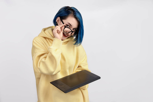 Una diseñadora femenina con capucha amarilla sosteniendo una tableta gráfica. El fondo blanco - Foto, imagen
