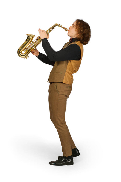 Portrait complet d'un jeune homme en chemise noire et costume marron clair avec gilet, jouant sur un saxophone isolé sur fond blanc - Photo, image