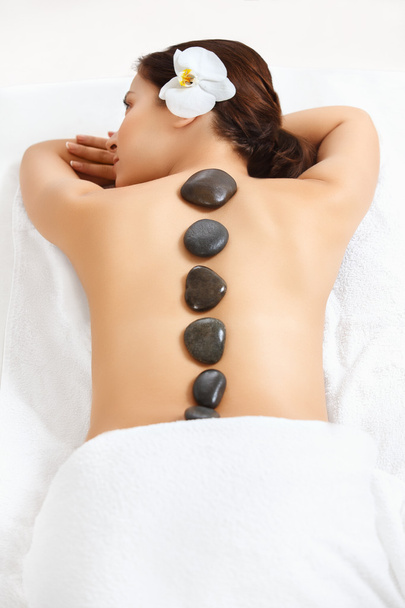 Stone Massage. Beautiful Woman Getting Spa Hot Stones Massage in - Zdjęcie, obraz