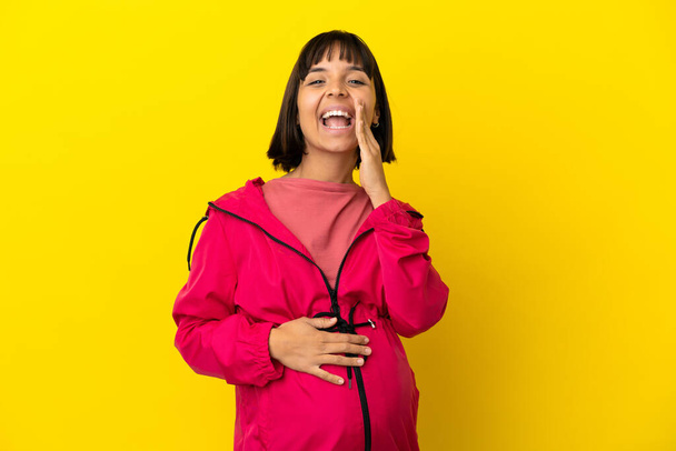 Молодая беременная женщина на изолированном желтом фоне кричит с широко раскрытым ртом - Фото, изображение