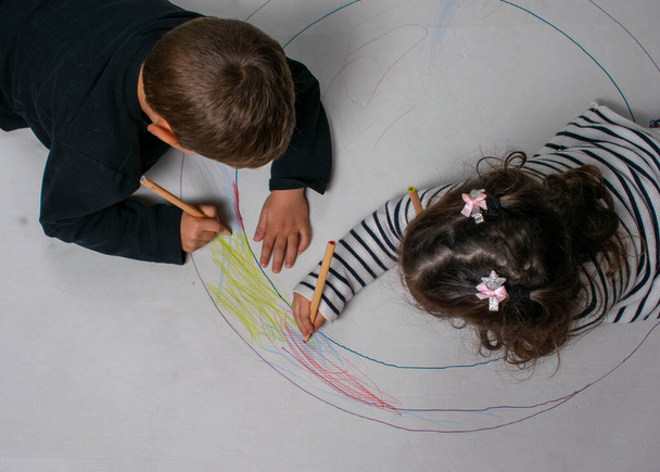 vista superior de um menino e menina desenho e pintura de uma bandeira gigante figuras geométricas no chão. - Foto, Imagem