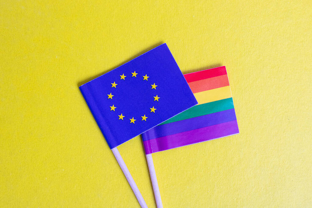 Small LGBT and EU flags on yellow background close up - Photo, Image