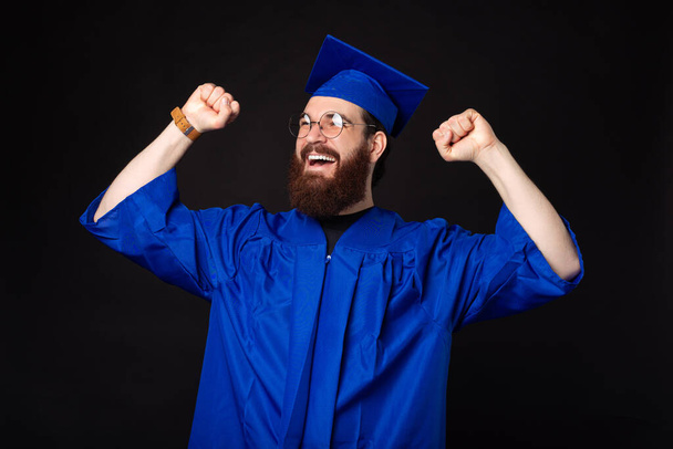 Amazed young student man celebrating and wearing blue bachelor. - Photo, Image