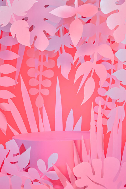 παστέλ ροζ έγχρωμη σκηνή με άδειο βάθρο και φύλλα ζούγκλας κομμένα σε χαρτί - Φωτογραφία, εικόνα