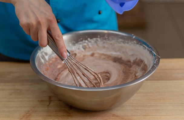 pétrit la pâte à la main dans un bol en métal avec un fouet à pâtisserie - Photo, image