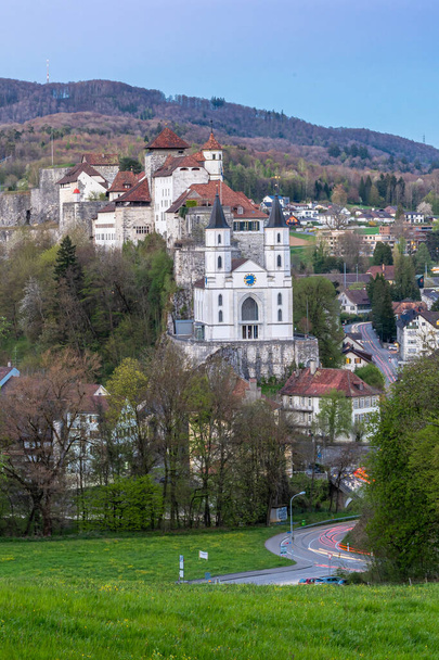Το κάστρο του Aarburg στην Ελβετία και μια μεταρρυθμισμένη εκκλησία βρίσκονται ψηλά πάνω από την πόλη Aarburg σε μια απότομη, βραχώδη πλαγιά. Σήμερα στεγάζει την καντονιακή φυλακή για αποκατάσταση ανήλικων παραβατών.. - Φωτογραφία, εικόνα