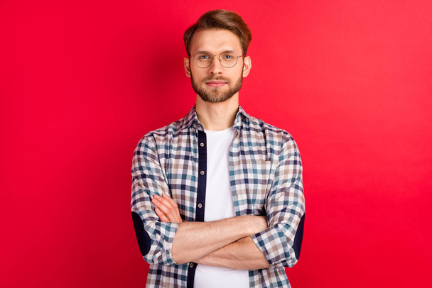 Photo of sweet confident young gentleman dressed plaid shirt spectacles arms crossed isolated red color background - Φωτογραφία, εικόνα