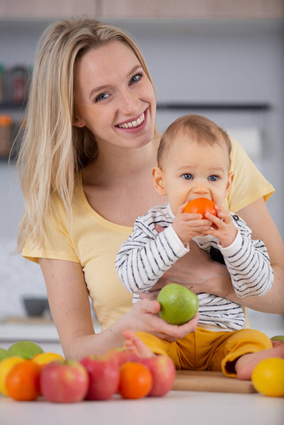young mother posing with baby and fruits - Foto, Imagen