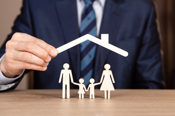 Begrip gezinsverzekering met handen die een gezin beschermen. Een dak boven het gezin - Foto, afbeelding