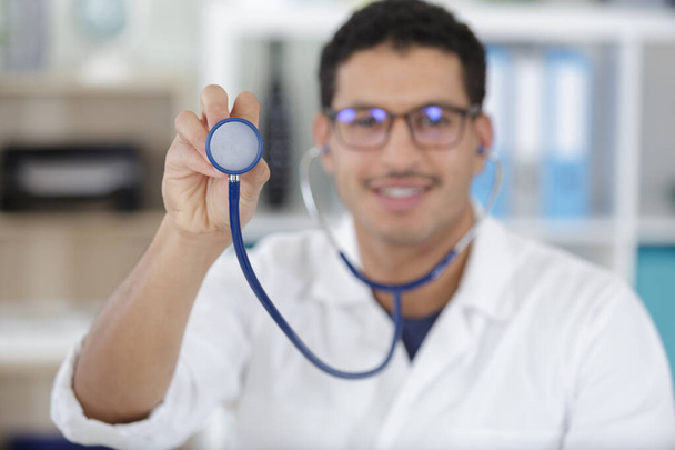 a smiling doctor showing stethoscope - 写真・画像