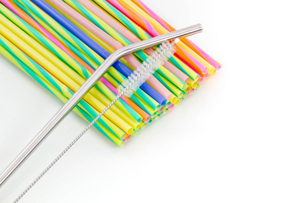 Reusable stainless steel straw with a cleaning brush above disposable plastic straws on a white background background. Zero waste concept. Copy space. - Photo, Image