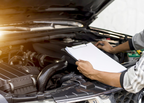 自動車整備士修理機械、車のサービスとメンテナンスのためのチェックリストをクリップボードへの書き込みを検査して車のエンジンをチェック. - 写真・画像