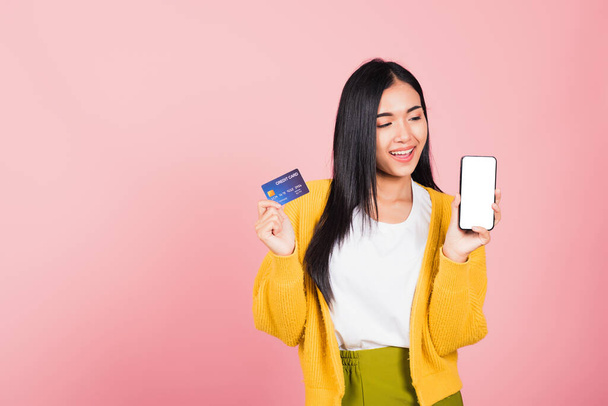 Happy Asian portrait beautiful cute young woman excited smiling hold mobile phone and plastic debit credit bank card, studio shot isolated on pink background, female using smartphone online shopping - Fotografie, Obrázek