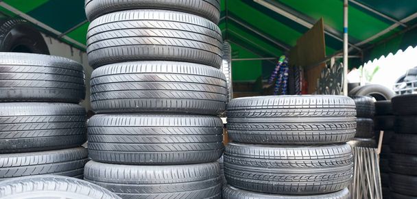 Muchos neumáticos están alineados bajo una tienda de lona verde. - Foto, imagen