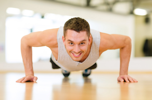 smiling man doing push-ups in the gym - Valokuva, kuva