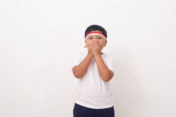 Asian kids with red white headband ribbon standing while cover her mouth. Isolated on white background. - Foto, Imagen