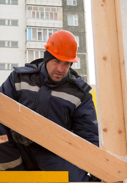 Ο εργαζόμενος καθορίζει το επίπεδο μιας ξύλινης ράβδου - Φωτογραφία, εικόνα
