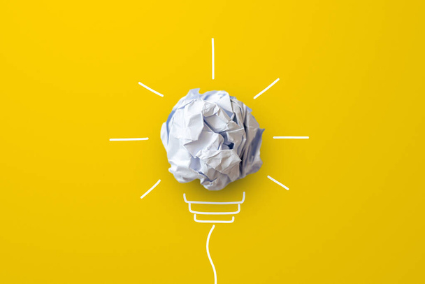 Luovat ajattelutavat ja innovaatiokonsepti. Paperiromu pallo hehkulamppu symboli keltaisella pohjalla - Valokuva, kuva