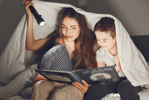 Mom and child reading a book with a flashlight - Photo, Image
