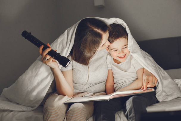 Η μαμά και το παιδί διαβάζουν ένα βιβλίο με φακό. - Φωτογραφία, εικόνα