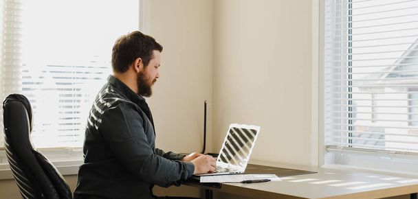 Männlicher Computerfreak sitzt am Schreibtisch und benutzt Laptop im Schrank. - Foto, Bild