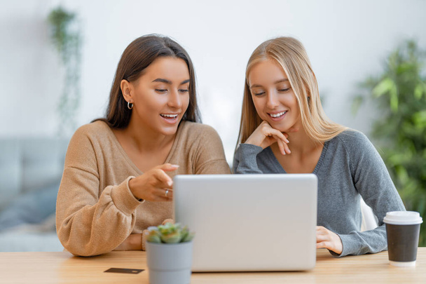 Two happy young women doing online purchases. Girls doing shopping at home. - Foto, afbeelding