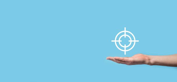 Targeting concept with hand holding target icon dartboard sketch on chalkboard. Objective target and investment goal concept - Photo, Image