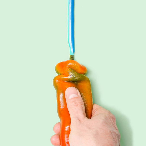 Abstract tube like concept, fresh organic unique shaped pepper squeezed toothpaste by male hand on pastel green background - Photo, Image