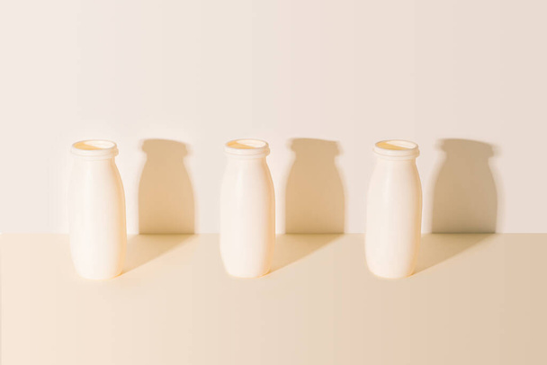 Modello di tre bottiglie di plastica usate riciclo. Disposizioni fatte su sfondo beige pastello con ombre soleggiate sul muro dietro. - Foto, immagini
