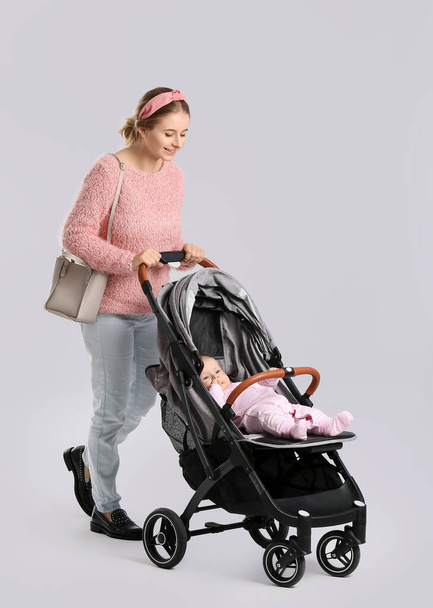 Frau und ihr süßes Baby im Kinderwagen auf weißem Hintergrund - Foto, Bild