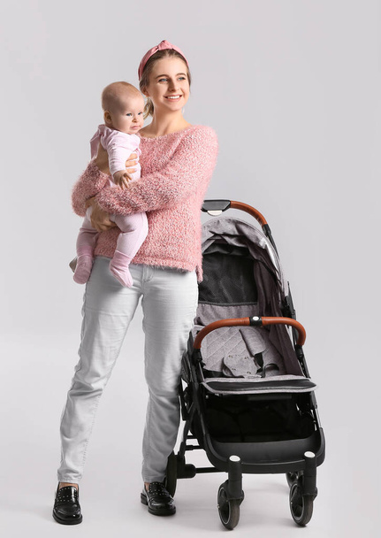 Vrouw met haar schattige baby en kinderwagen op witte achtergrond - Foto, afbeelding
