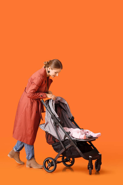 Woman and her cute baby in stroller on color background - Foto, Bild