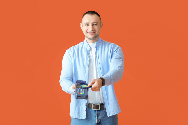 Uomo con terminale di pagamento e carta di credito su sfondo a colori - Foto, immagini