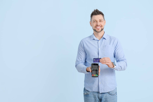 Man with payment terminal and credit card on color background - Fotografie, Obrázek