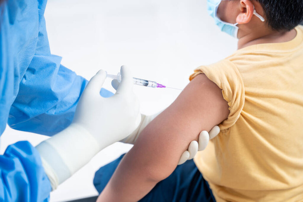 Kezelőorvos közelsége, aki vakcinázást végez a beteg fiú vagy gyermek vállán, injekció a karba, koronavírus, kovid-19 oltási betegség, felkészülés a humán klinikai vizsgálatokra oltás - Fotó, kép
