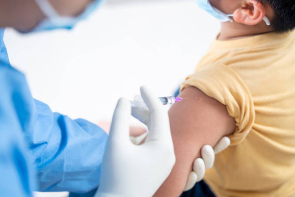 Lääkäri, joka tekee rokotuksen potilaan pojan tai lapsen olkapäähän, influenssarokotus Injektio käsivarteen, sepelvaltimovirus, covid-19 rokote tauti valmistautuu ihmisen kliinisiin tutkimuksiin rokotus laukaus - Valokuva, kuva