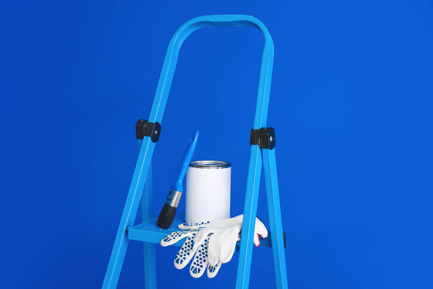 Ladder met blik verf, borstel en handschoenen in de buurt van kleur muur - Foto, afbeelding