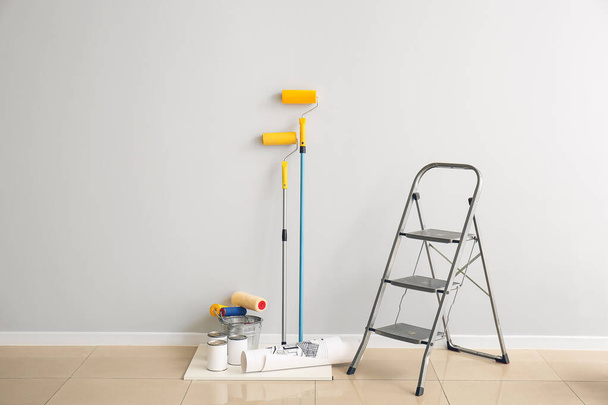 Ladder, cans of paints and rollers near light wall - Fotoğraf, Görsel