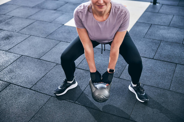 Usmívající se atletická žena předvádí obouruční kettlebell deadlift - Fotografie, Obrázek